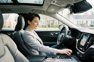 Femme au volant d'une voiture automatique en leasing, main posée sur le levier de vitesse, intérieur moderne